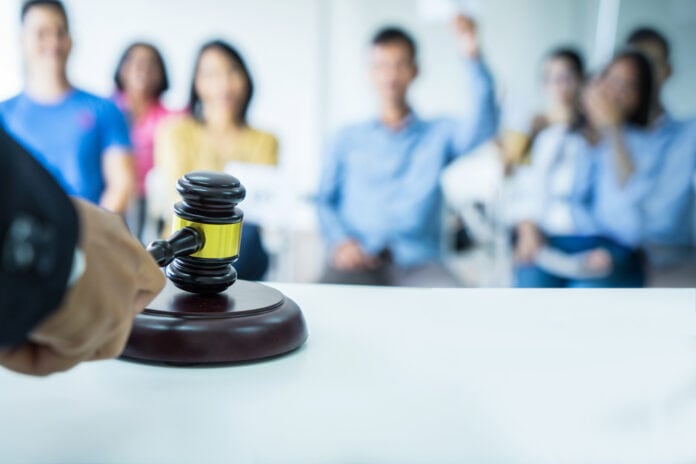 Close,Up,Auctioneer,Hand,,Black,Suite,,Holding,Gavel,,Wooden,Hammer,