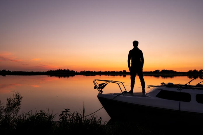 A,Silhouette,Of,A,Young,Man,Standing,On,A,Boat