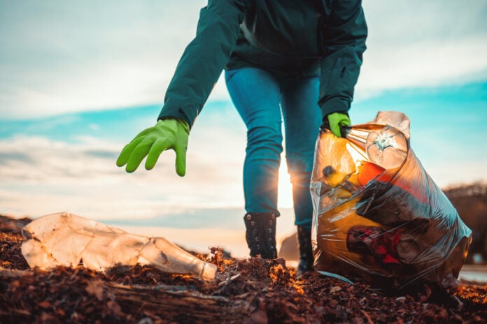A,Volunteer,Collects,Garbage,On,A,Muddy,Beach.,Close-up.,The